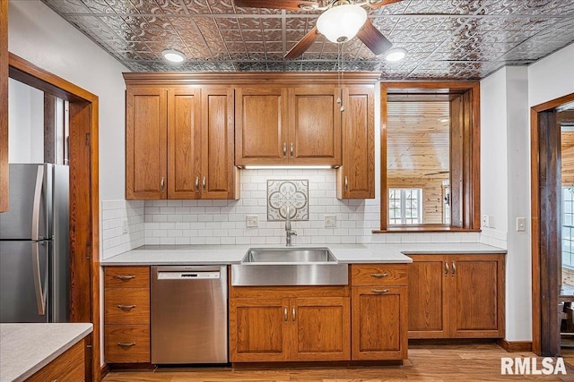kitchen featuring brown cabinets, an ornate ceiling, a sink, and appliances with stainless steel finishes
