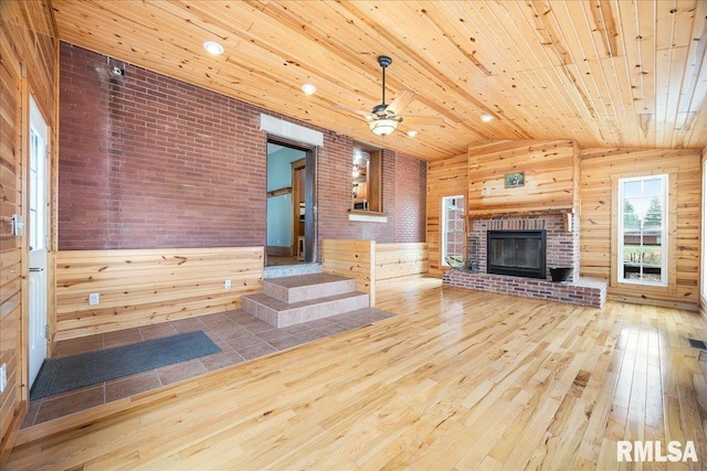 unfurnished living room featuring an outdoor brick fireplace, wood-type flooring, wood ceiling, wood walls, and lofted ceiling