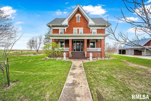 view of front facade featuring brick siding, a porch, and a front lawn