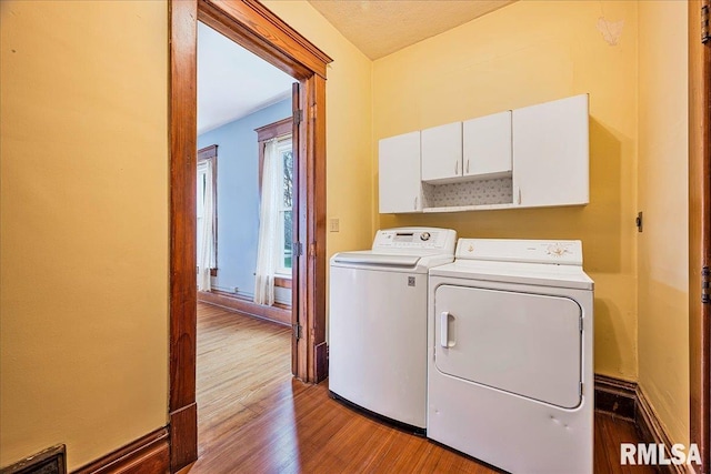 laundry room featuring visible vents, washer and clothes dryer, cabinet space, and wood finished floors