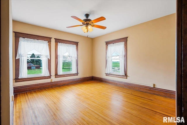 empty room with baseboards, hardwood / wood-style floors, and a ceiling fan