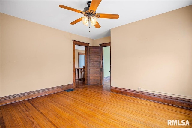 spare room featuring light wood-type flooring, ceiling fan, baseboards, and visible vents