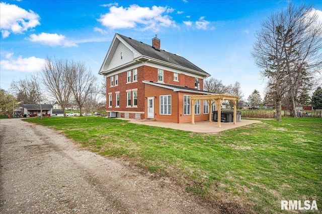 rear view of house with a pergola, a patio area, a yard, and a chimney