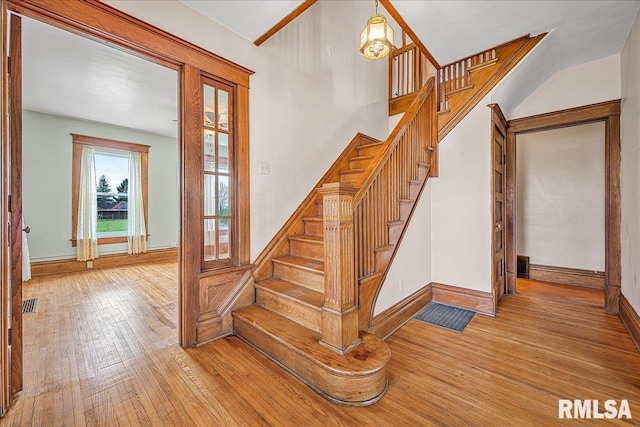 staircase with visible vents, wood-type flooring, and baseboards