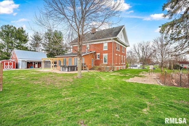 rear view of house featuring a hot tub, a yard, an outdoor structure, a barn, and a chimney