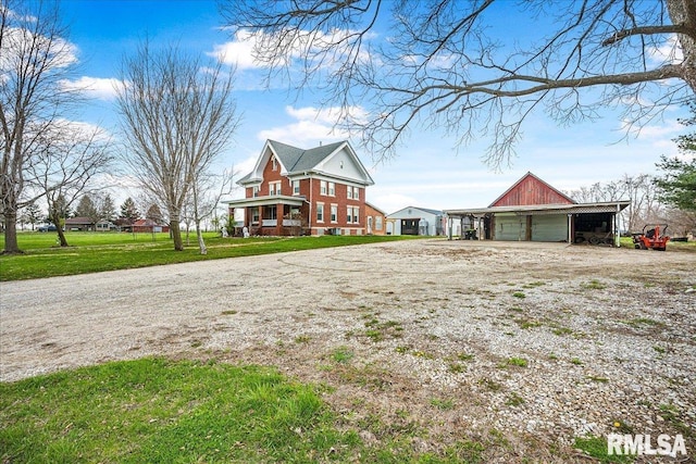 view of front of house featuring an outbuilding, a pole building, dirt driveway, a detached garage, and a front yard