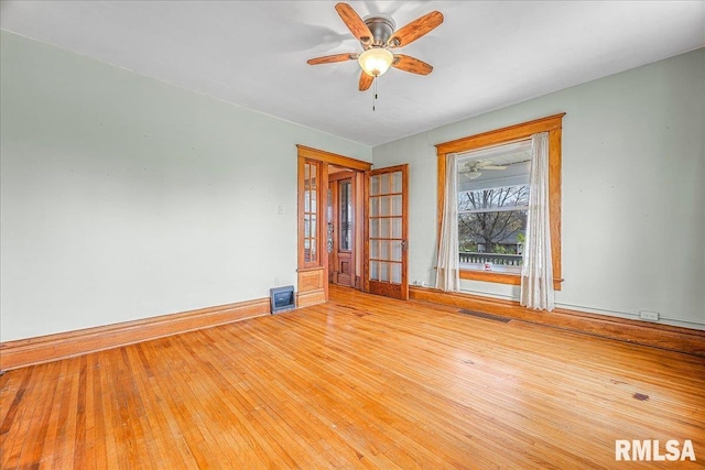 spare room with visible vents, ceiling fan, wood-type flooring, and baseboards