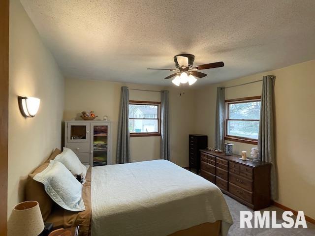bedroom featuring ceiling fan, a textured ceiling, and multiple windows