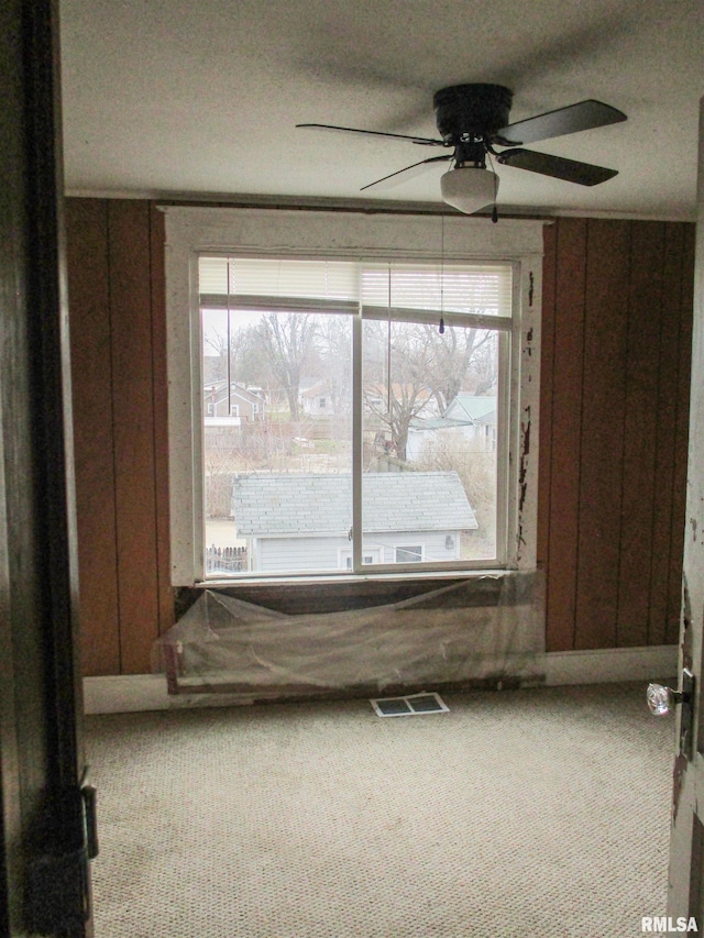 carpeted empty room featuring visible vents and a ceiling fan