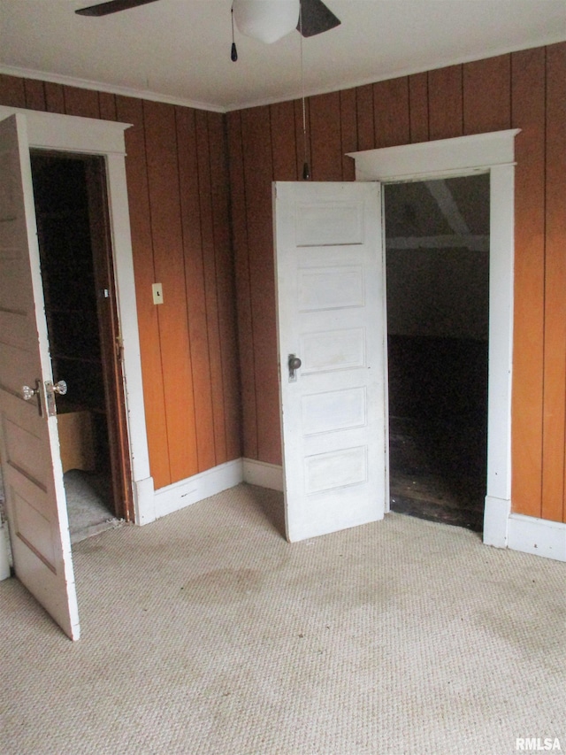 unfurnished room with wooden walls, ceiling fan, baseboards, and light carpet