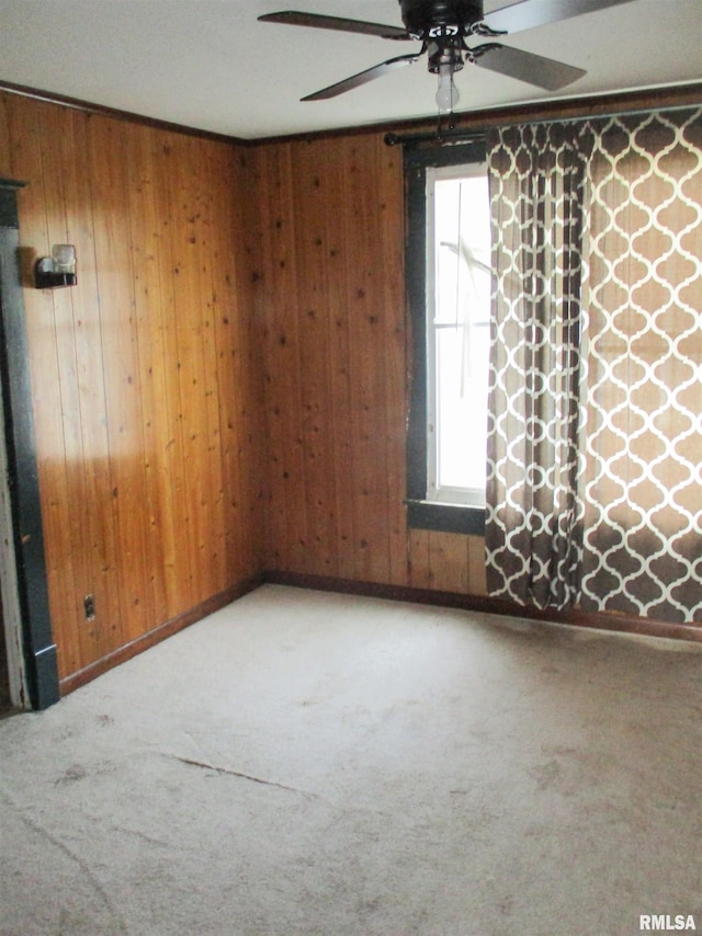 unfurnished room with wood walls, carpet floors, and ceiling fan