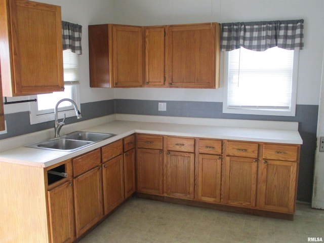 kitchen with light countertops, brown cabinetry, and a sink