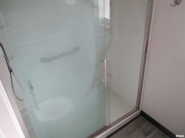 full bathroom featuring baseboards, wood finished floors, and a stall shower