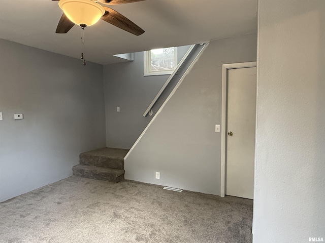 below grade area with carpet, a ceiling fan, and stairs
