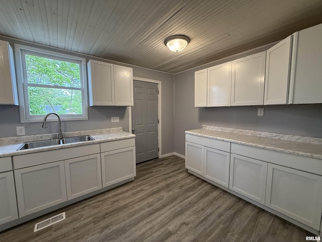 kitchen featuring a sink, light countertops, dark wood-style floors, baseboards, and wood ceiling