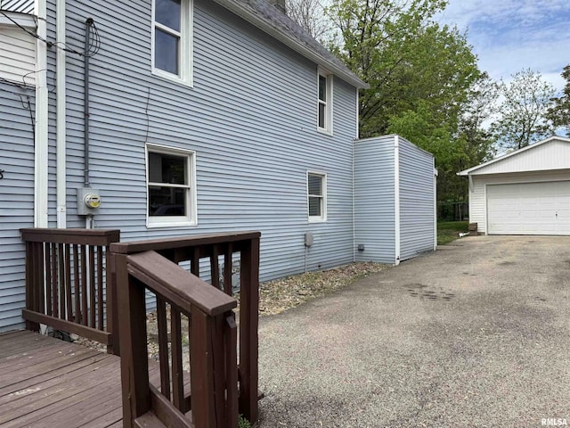 view of side of property with a wooden deck, an outbuilding, and a detached garage