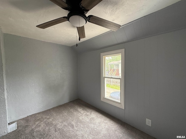 carpeted empty room with a ceiling fan, a textured wall, and lofted ceiling