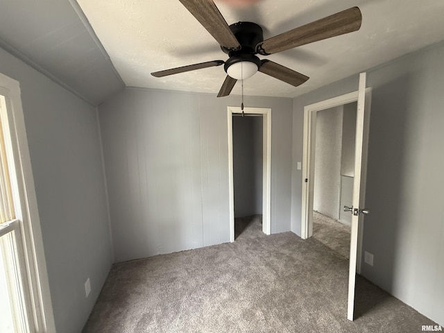 unfurnished bedroom featuring carpet flooring, a closet, a ceiling fan, and lofted ceiling