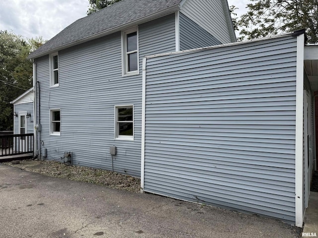 view of home's exterior featuring a deck and roof with shingles