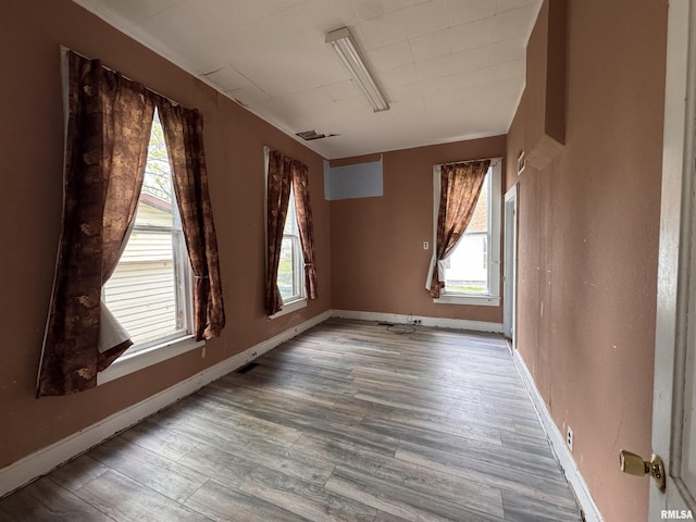 empty room featuring visible vents, baseboards, and wood finished floors