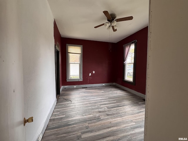 empty room featuring ceiling fan, baseboards, and wood finished floors