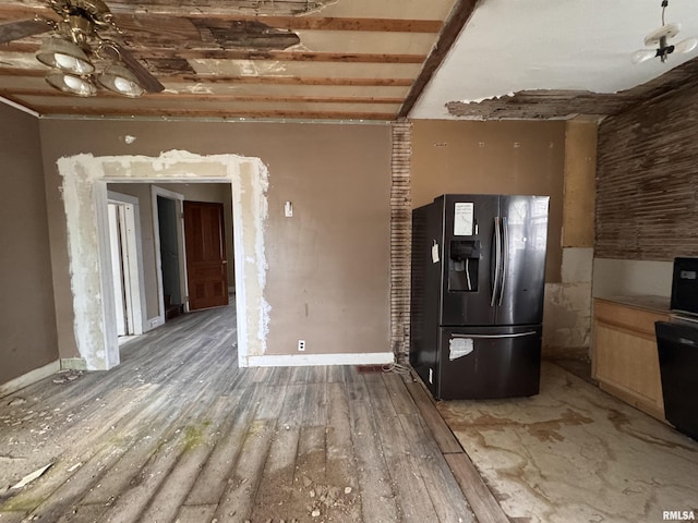interior space featuring black fridge with ice dispenser, baseboards, wood finished floors, and a ceiling fan