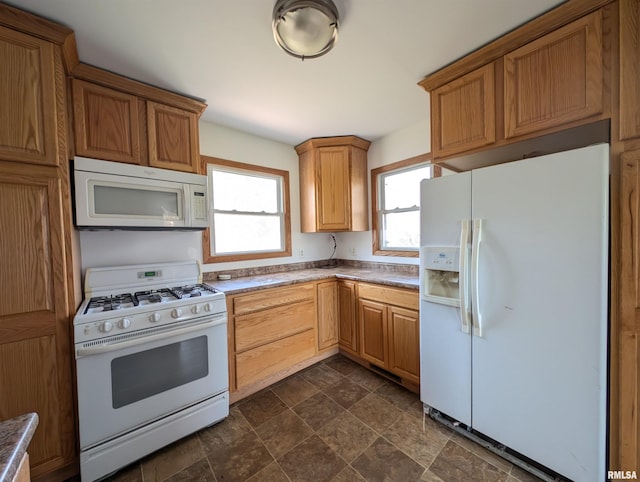 kitchen featuring plenty of natural light, stone finish flooring, and white appliances