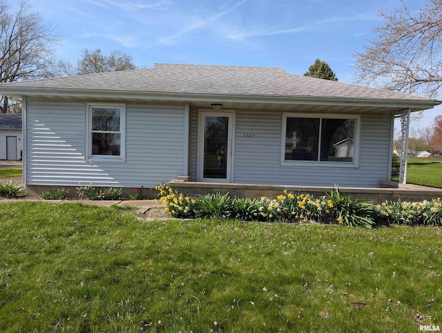 view of front of house with roof with shingles and a front yard