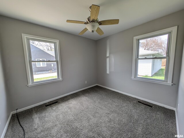 carpeted empty room with visible vents, baseboards, and ceiling fan
