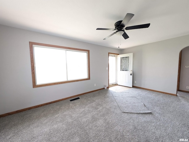 unfurnished room featuring arched walkways, baseboards, visible vents, and light colored carpet