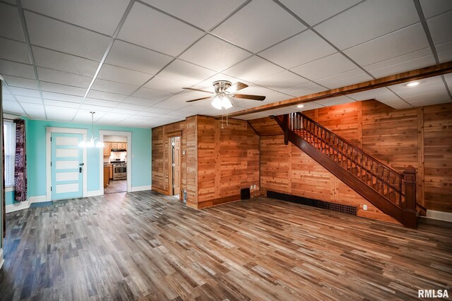 238 E Prospect St, Galesburg, IL 61401 - unfurnished living room featuring baseboards, wood finished floors, wood walls, stairway, and ceiling fan