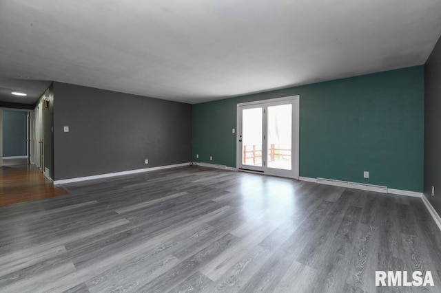 unfurnished living room with wood finished floors, baseboards, and baseboard heating