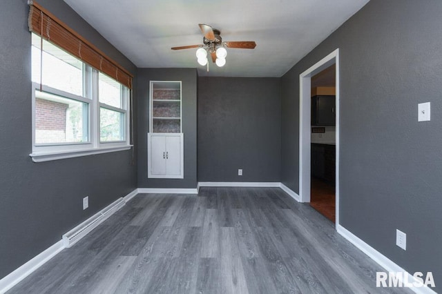 spare room with baseboards, dark wood-style floors, and ceiling fan