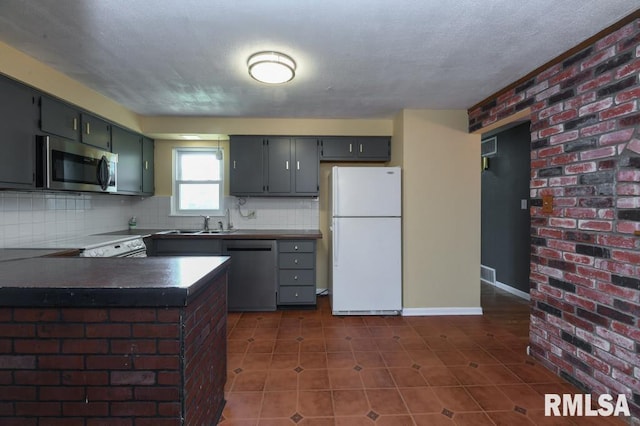 kitchen with stainless steel appliances, dark tile patterned floors, backsplash, and dark countertops