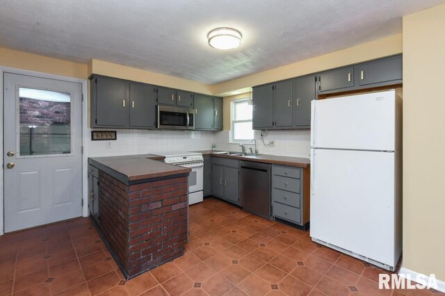 kitchen featuring a peninsula, tasteful backsplash, dark countertops, dark tile patterned flooring, and appliances with stainless steel finishes