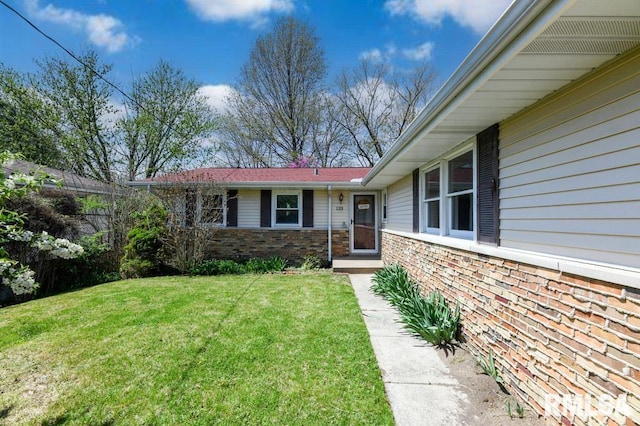 exterior space with brick siding and a yard