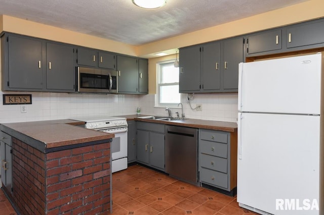 kitchen with dark countertops, a sink, backsplash, and appliances with stainless steel finishes