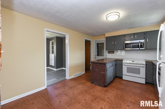 kitchen with white electric stove, a peninsula, stainless steel microwave, decorative backsplash, and gray cabinetry