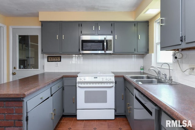 kitchen featuring white range with electric cooktop, a sink, dishwasher, stainless steel microwave, and a peninsula
