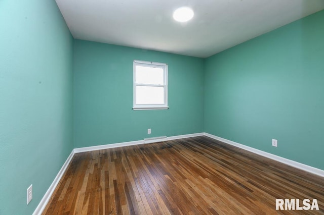 empty room with dark wood finished floors, visible vents, and baseboards