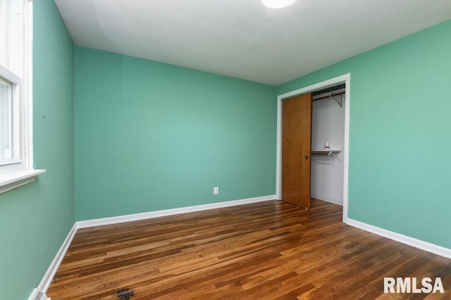 unfurnished bedroom featuring wood finished floors, a closet, and baseboards