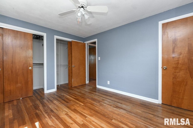 unfurnished bedroom with two closets, baseboards, a ceiling fan, and wood finished floors