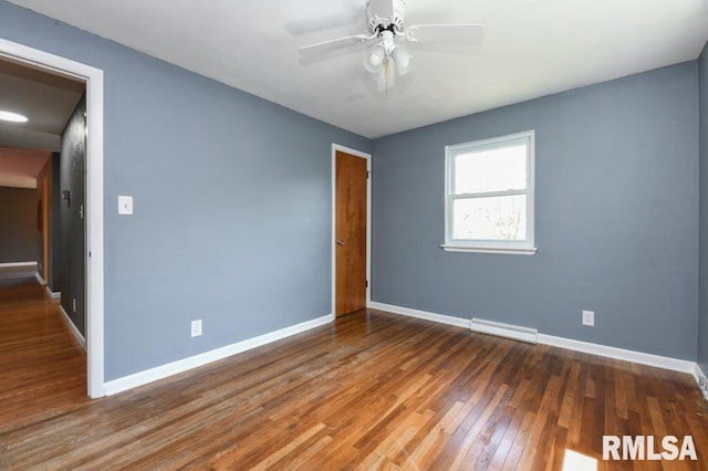 empty room featuring a baseboard radiator, baseboards, wood-type flooring, and ceiling fan