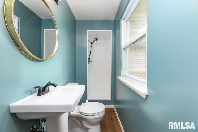 bathroom featuring baseboards, toilet, wood finished floors, and walk in shower