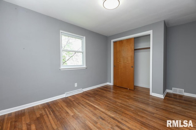 unfurnished bedroom with baseboards, hardwood / wood-style flooring, visible vents, and a closet