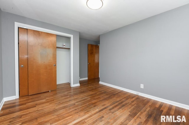unfurnished bedroom featuring wood finished floors, a closet, and baseboards
