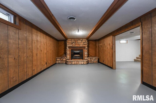 basement with wood walls, stairs, visible vents, and a fireplace