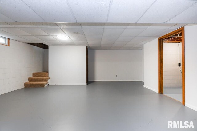 finished basement featuring concrete block wall, baseboards, and stairs