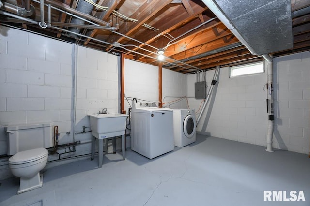 laundry room with electric panel, concrete block wall, a sink, washer and clothes dryer, and laundry area
