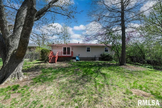 back of property with a wooden deck, a lawn, and fence